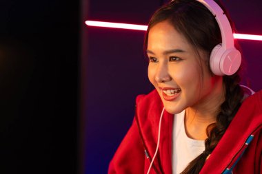 Portre sunucusu güzel Asyalı kız flamasının çevrimiçi oyun oynaması kulaklık takması pastel renkli konuşmalar izleyici medyası ile çevrimiçi. Esport yetenekli takım oyuncuları neon mavi odada. Taktik.