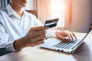 Genç adam, laptop bilgisayar başvurusu ya da web sitesinde online alışveriş yapmak için kredi kartı kullanıyor. E-ticaret ve online alışveriş konsepti. uds