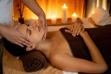 Beyaz kadın stres önleyici kafa masajı yapmaktan ve lüks otel veya otelde sıcak mum ışığında yüz güzelliği eğlencesi yapmaktan zevk alıyor. Sessiz.