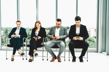 İş kadınları ve işadamları iş görüşmesi için koltuklarda beklerken cep telefonu kullanıyorlar. Şirket işi ve insan kaynakları kavramı. uds