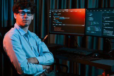 Uygulama ekranı arkaplanındaki kodlama programında gece vakti çevrimiçi yazılım geliştirme bilgisiyle kameraya bakan IT geliştiricisi güncellenmiş yazılım donanımı yaratıyor. Toplayıcı.