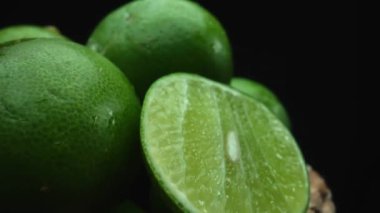 Limon dilimleri titizlikle bir yığın halinde, siyah arkaplana göre dizilmiş. Her bir kireç dilimi çarpıcı detaylar, canlı yeşil rengi ve baştan çıkarıcı dokusu ile yakalanır. Kapatın. Geliştirilebilir.