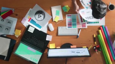 Akıllı iş adamının logo grafiği tasarlarken renk paletleri seçmesinin üst görünümü. Profesyonel iç mimar tasarımının hava görünümü ve renk paletleri kullanarak renk temasını seçin. Sempozyum.