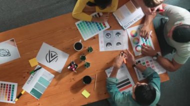 Proje yöneticisi renk paletleri seçerken tasarımcının tablete baktığı yukarıdan aşağıya hava görüntüsü. Profesyonel grafik tasarımının en üst görüntüsü ve logoya bakın. Yetenekli ekip grafikleri seçiyor. Sempozyum.