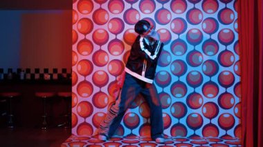 Asyalı break dansçı serbest stile geçiyor ve balon arka planlı kameraya bakıyor. Profesyonel hippi gündelik kıyafet giyer ve gözlük takar. Mutluluk.