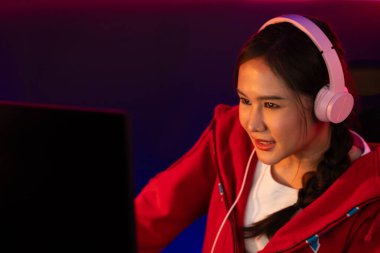 Portre sunucusu güzel Asyalı kız flamasının çevrimiçi oyun oynaması kulaklık takması pastel renkli konuşmalar izleyici medyası ile çevrimiçi. Esport yetenekli takım oyuncuları neon mavi odada. Taktik.