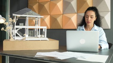 Laptop analizi ev modeli yapısını kullanan İspanyol mimar el mühendislerinin yakın çekimi. Proje yöneticisi dizüstü bilgisayarda yazarken ev modeli inşaatını kontrol ediyor. Tasarım konsepti. Yönlendirici.