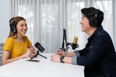 Gülümseyen radyo etkili sunucusu kulaklık takıyor kadın konuşmacı ile röportaj yapıyor sosyal medya internet sitesinden dinleyicilere bilgi paylaşıyor stüdyo kaydında sabah canlı yayın kanalı. İnfobahn.