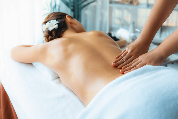 Caucasian woman customer enjoying relaxing anti-stress spa massage and pampering with beauty skin recreation leisure in day light ambient salon spa at luxury resort or hotel. Quiescent