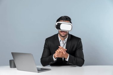 Meta-evrene girmek için VR cam takan bir iş adamı oturuyor ve bilgisayarı açıyor. Akıllı yönetici sanal gerçeklik kulaklığını kullanarak veri analizine bağlanıyor ve yatırım için karar veriyor. Sapma.