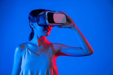 Akıllı kadın, metaevrene bağlı, fütürist siber uzay teknolojisine sahip VR kulaklık takıyor. Zarif kadın sanal alana bakarken kendine güvenerek poz veriyor. Halüsinasyon.