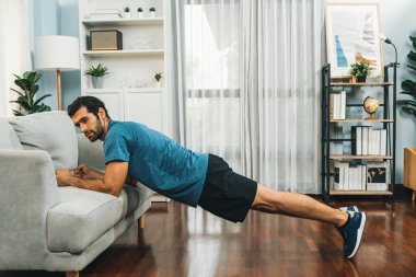 Atletik vücut ve aktif sporcu, sağlıklı vücut çalışma yaşam tarzı konsepti olarak neşeli ev egzersizlerinde kas kazanma egzersizi yapmak için mobilyaları kullanıyor..