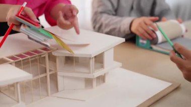 Ev tasarımcısı mimari ekipman kullanarak bir plan çizerken, iç tasarımcı da müşterilerin talebine göre renk örneklerinden uygun renkler seçiyor. Değiştirilmiş