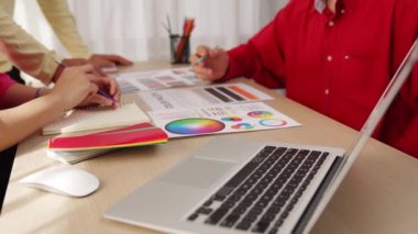 Dizüstü bilgisayarla çalışan grafik tasarım için beyin fırtınası yapan ve renk seçimi yapan tasarımcı takımının yavaş çekim çekimleri. Bu sırada müşteri de ofiste kromatik danışma sırasında projeyi denetliyor. Değiştirilmiş