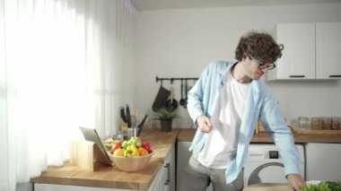 Mutlu baba yemek pişirirken müziğe geçiyor ve modern mutfakta öğle yemeği hazırlıyor. Aktif baba, sebze ve mutfak gereçleri ile çevrili sağlıklı yemek ya da salata yaparken şarkıyla dans ediyor. Pedagoji.