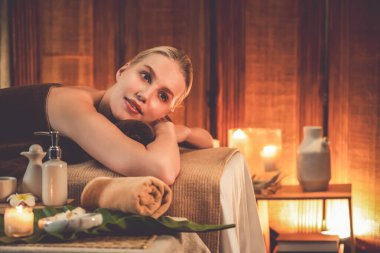 Beyaz kadın müşteri stres önleyici spa masajının keyfini çıkarıyor ve lüks otel ya da otelde sıcak mum ışığında güzellik teniyle eğleniyor. Sessiz.