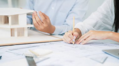 Profesyonel mühendis ev modelini tartartarken, yetenekli tasarımcı da planına yazar. Birlikte çalışmak, işbirliği, işbirliği. Yaratıcı tasarım ve takım çalışması konsepti. - Yakın çekim. Tertemiz.