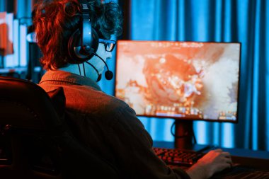 Savaş arenasında çoklu oyunlar takımıyla Moba 'da savaşan genç oyun flamasının sunucu kanalı, neon dijital ışık modern odasındaki arka görüntü ile bilgisayar monitöründe kulaklık takıyor. Toplayıcı.