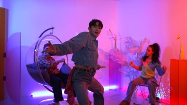 Çok kültürlü bir arkadaş kürsüde otururken Asyalı yetenekli bir dansçı modern müziğe geçiyor. Profesyonel dansçı, hipster takımı tezahürat yaparken ve desteklerken enerjik adımlar atıyor. Mutluluk.