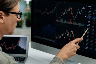 Akıllı yatırımcılar bilgisayar ekranlı ilginç borsa takasını işaret ediyorlar. Finansal teknoloji dinamik yatırım planı modern işyerindeki veri grafiğine odaklanıyor. Bireysel.
