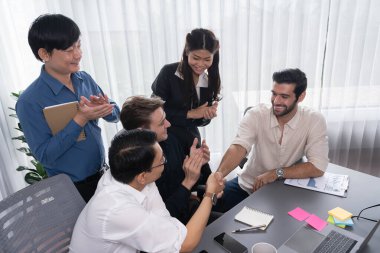 Çeşitli ofis çalışanları stratejik iş pazarlama toplantısı üzerine anlaşma yaptıktan sonra el sıkışıyor. Takım çalışması ve olumlu tutum verimli ve destekleyici bir iş yeri yaratır. Tedbirli