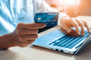 Genç adam, laptop bilgisayar başvurusu ya da web sitesinde online alışveriş yapmak için kredi kartı kullanıyor. E-ticaret ve online alışveriş konsepti. uds
