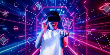 VR gözlük takan zeki bir genç ve geometrik şekil konusunda heyecanlı. Afrikalı oyuncu gündelik kıyafet giyiyor ve artırılmış gerçeklik teknolojisi kullanırken parlak ışık rengiyle çevrili. Yaratıcılık.
