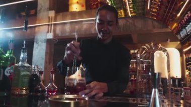 Zeki Asyalı barmen bardakta karıştırılmış alkol şurubunu buzla karıştırıyor. Çünkü kayanın üzerinde kamera var. Gece kulübünde taze kokteyl kokteylleri karıştırıyor. Vinosity.