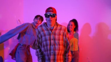 Mutlu hipster stüdyoda neon ışıklı kameraya bakarken süslü gözlük takıyor. Komik mutlu dans takımı hip hop kafiyesine ya da modern pop müziğiyle beyaz sanatçıya taşınıyor. Mutluluk.