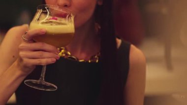 Kapanışta güzel bir kadın, gece kulübü tezgahı partisinde gece yarısı sıcak ışıklarıyla hindistancevizli, köpüklü içeceğe cam karıştırılmış meyve suyu kokteyli hazırlıyor. Vinosity.