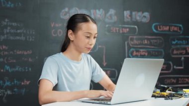Kara tahtada dizüstü bilgisayar kullanarak akıllı kız programlama sistemi. Lise öğrencisi mühendislik kodları yazıyor ya da STEM teknoloji sınıfındaki kameraya bakarken bir şey söylüyor. Yaratıcı eğitim. Öğretim