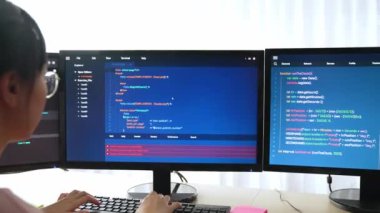 Yavaş çekim arkası yazılım geliştirici mühendisi bilgisayar programlama için birlikte çalışarak hata ayıklama kodunu çözüyor, ofiste monitörde karmaşık algoritmaları çözüyor. Filizlenen