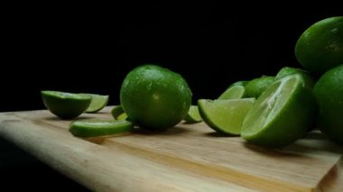 Yakın plan, canlı bir dilim taze kireç kırsal bir ahşap kesme tahtasının üzerinde duruyor. Tazelik ve canlılık yayıyor. Kesme tahtasına konmuş yeşil limon diliminin yarı saydam zarları. Geliştirilebilir.