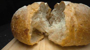 Koyu arkaplanda taze ekmek parçacıkları var. Tahta tepsiye yerleştirilmiş ekmeğin makro fotoğrafçılığı. Kamera hareketini yakınlaştır. Gurme ve fırın konsepti. Poster için tasarım, yemek blogu. Pabulum.