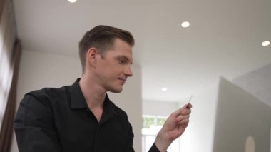 Genç adam internet bankacılığı için kredi kartlı dizüstü bilgisayar kullanıyor. İnternet üzerinden alışveriş yapıyor. Banka kartıyla modern ve kullanışlı online satın alma. Düzenle