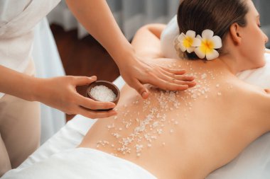 Lüks spa salonlarında sıcak mum ışığında cilt bakımı yaptıran kadın müşteri. Sağlık Spa vücut fırçasında tuz temizleme güzellik tedavisi. Sessiz.