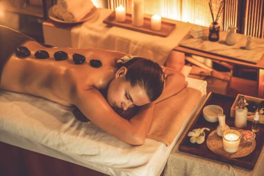 Lüks tatil köyündeki kaplıcalarda sıcak taş masajı, sıcak mum ışığı, spa bazalt taşı masajının keyfini çıkaran mutlu kadın müşteriler, rahatlatıcı bir sıcaklıkla vücudun üzerinde süzülüyorlar. Sessiz.