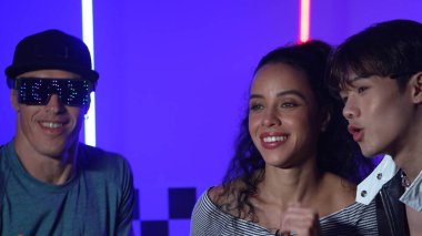 Gündelik tişörtlü mutlu İspanyol kız neon ışıklı çeşitli break dansçılarla dans ediyor. Profesyonel sokak dansçısı ev ve parti ışıklarıyla serbest stil müzik yapıyor. Mutluluk.