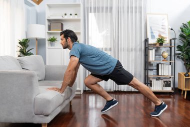 Atletik vücut ve aktif sporcu, sağlıklı vücut çalışma yaşam tarzı konsepti olarak neşeli ev egzersizlerinde kas kazanma egzersizi yapmak için mobilyaları kullanıyor..