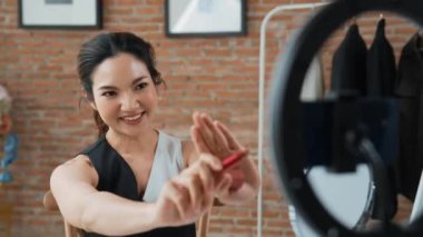 Kadın nüfuzlu kişi canlı yayın yapan video görüntülerini sosyal medya ya da blog üzerinden gözden geçiriyor. Kozmetik stüdyosu ışıklandırmalı mutlu genç kız çevrimiçi pazarlama oturumu yayını için..