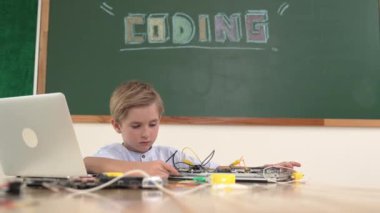Kök sınıfında tahtayla otururken elektronik tahtada çalışan bir öğrenci. Çocuk, kodlama mühendisliği ve yapay zeka kullanarak programlama sistemine hazırlanırken ana tahtayı tamir ediyor. Pedagoji.