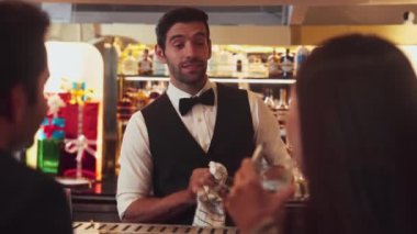 Lüks tezgah barında müşteri çiftiyle konuşurken bardakları silip gülen zeki barmenler, canlı bir gece partisi atmosfer gece kulübünde özel içecekler hazırlıyorlar. Vinosity.