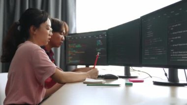 Yavaş çekim arkası yazılım geliştirici mühendisi bilgisayar programlama için birlikte çalışarak hata ayıklama kodunu çözüyor, ofiste monitörde karmaşık algoritmaları çözüyor. Filizlenen