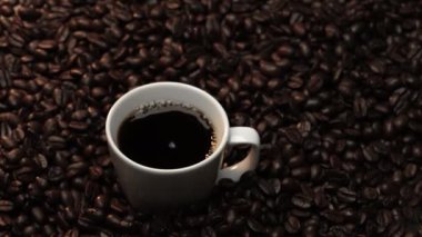 Kahve çekirdeğini yaklaştır ve kahve çekirdeği yığınıyla birlikte sıcak espresso 'ya bırak. Makro taze kavrulmuş fasulye aromatik dumanla bardağa düşüyor. Ağır çekim. Organik kahve tohumu kavramı. Geliştirilebilir.