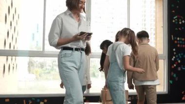 Çeşitli çocuklar sandalye kapmaca oynarken genç ve güzel öğretmenler müziği kapatıyor. Çok kültürlü öğrenciler yaratıcı aktivitelerde sandalyede koşup oturuyorlar. Müzik dersi. Etkinlik.