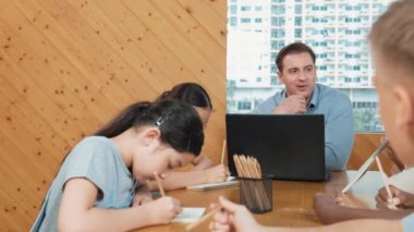 Profesyonel Kafkas öğretmeni çeşitli öğrenciler test yaparken ev ödevini açıklıyor. Çok kültürlü liseli çocuklar sınıfta otururken kağıda cevap yazıyorlar. Yaratıcı eğitim. Öğretim