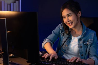 Gülümseyen güzel Asyalı yaratıcı kadın telefon masasından müşteriye ya da iş arkadaşına arıyor yaratıcının projelerini açıklarken geceleri neon ofisteki pazar analizini araştırıyor. Taktik.