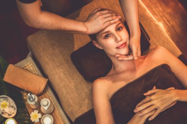 Beyaz kadın stres önleyici kafa masajı yapmaktan ve lüks otel veya otelde sıcak mum ışığında yüz güzelliği eğlencesi yapmaktan zevk alıyor. Sessiz.