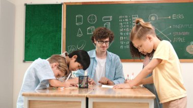 Zeki öğretmen, çeşitli çocuklar sınıf çalışması yapmak için birlikte çalışırken farklı çocukların zihin haritası çizdiği fikri açıklıyor. Çekici eğitmen öğretmek ve çalışmak hakkında konuşmak. Pedagoji.