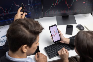 İki iş adamının internet sitesindeki dinamik borsa tartışmalarına odaklanan üst görünüm, modern ofisteki gerçek zamanlı döviz kuru risk verilerindeki bilgisayar ekranlarıyla karşılaştırılıyor. Varsayım.